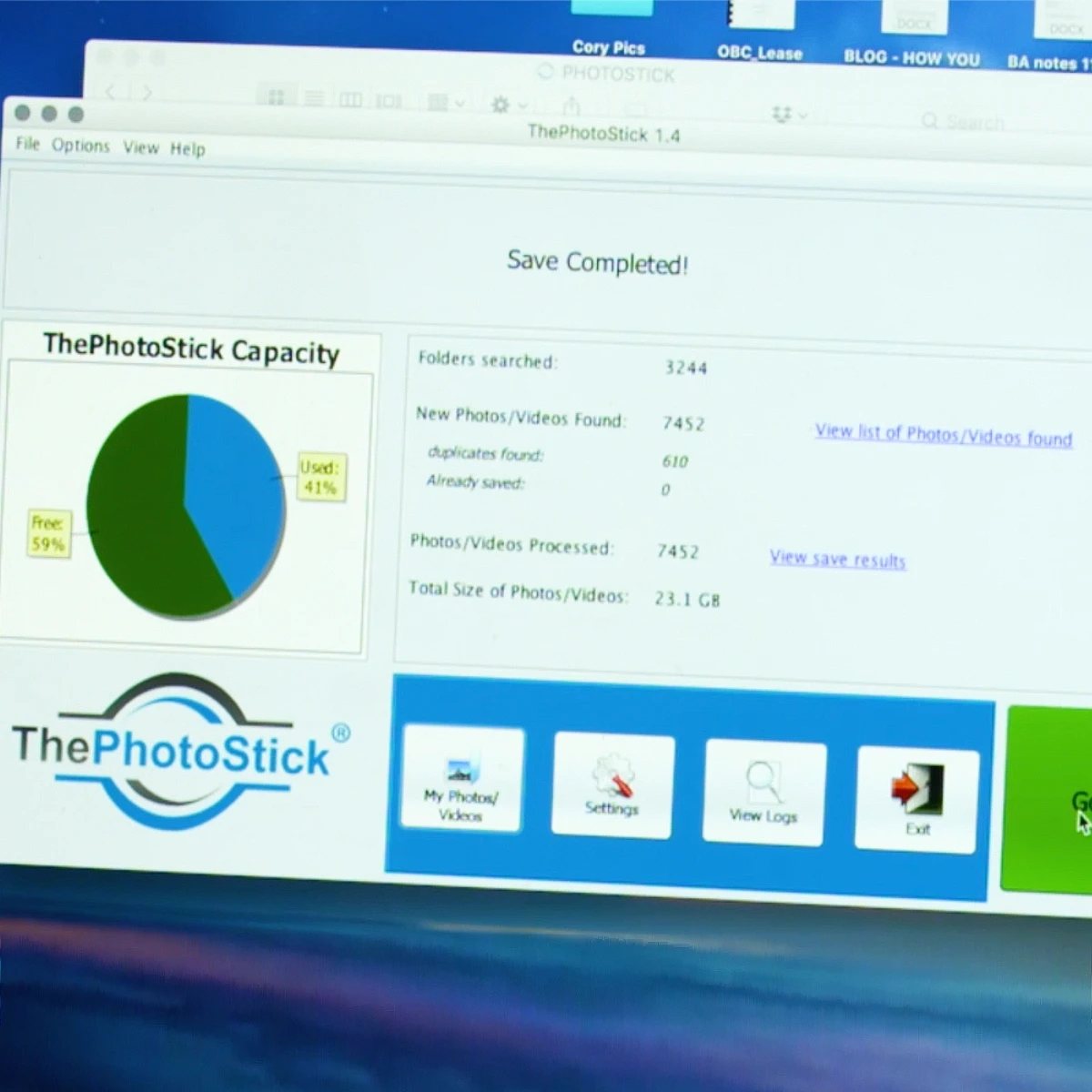 ThePhotoStick software window showing a backup in progress on a laptop