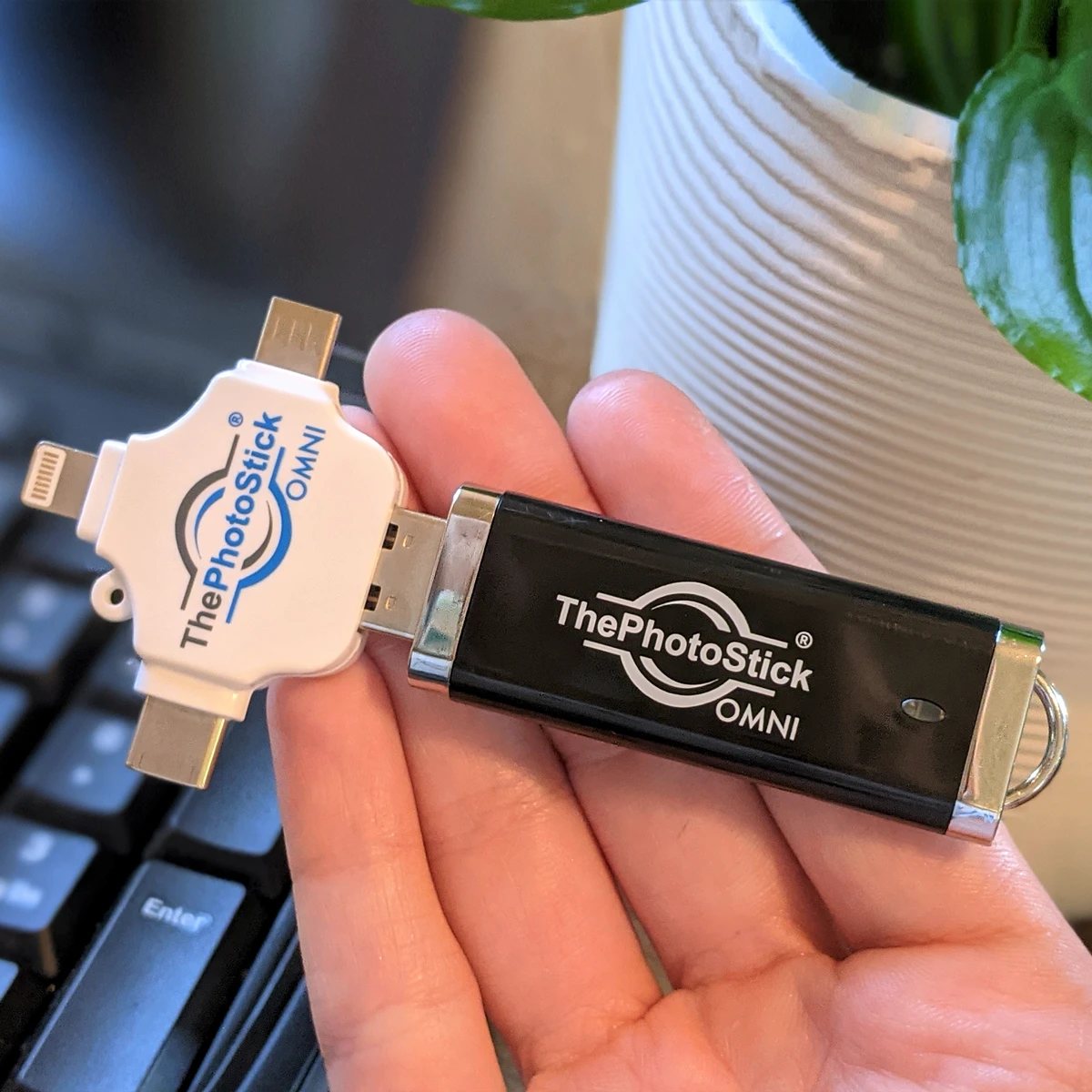Hand holding ThePhotoStick OMNI USB backup device with its multi-connector tip